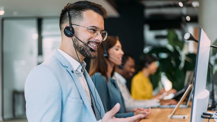 Customer service representative wearing a headset while working at a computer.