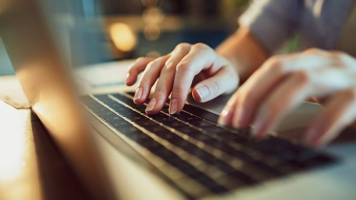 Close-up of hands typing on a laptop keyboard, emphasizing data minimization for responsible data stewardship and security.