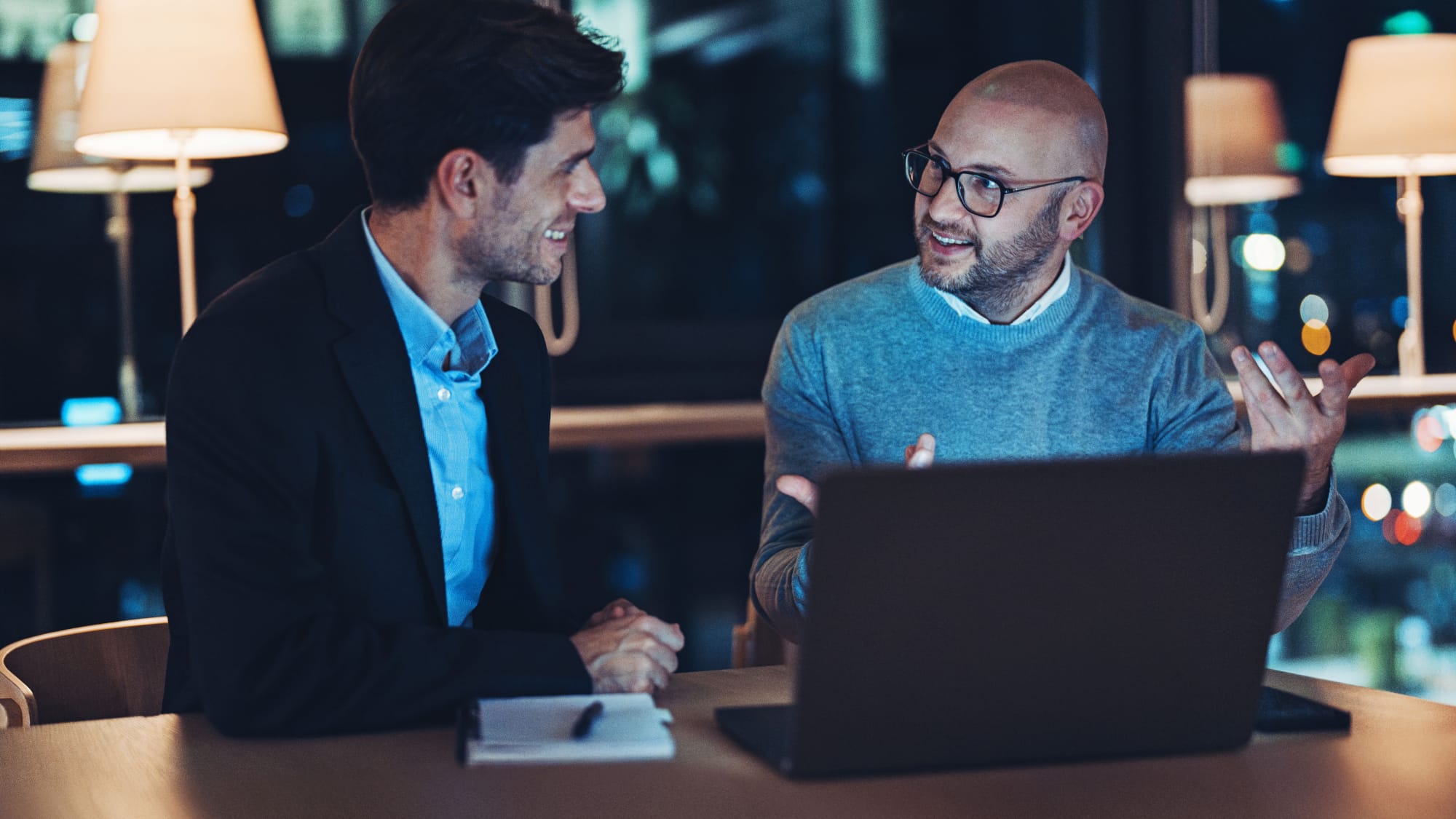Two financial professionals review regulatory and industry updates during a meeting with a laptop.