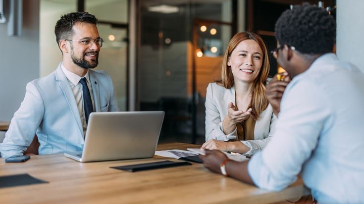 Three professionals meeting around a conference table to discuss strategies for strengthening employee risk management programs.
