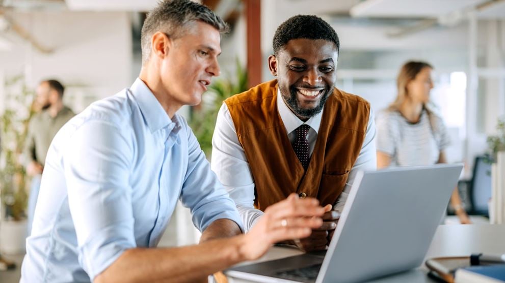 Professionals collaborating on a laptop, representing a strategic approach to customer onboarding.