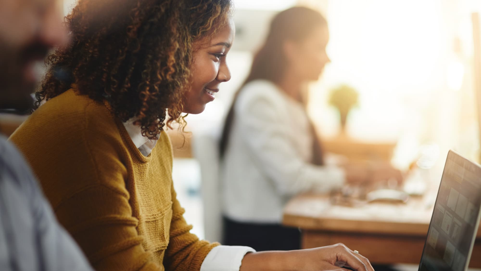 A woman focused on her laptop, typing as she engages with financial crime prevention trends.