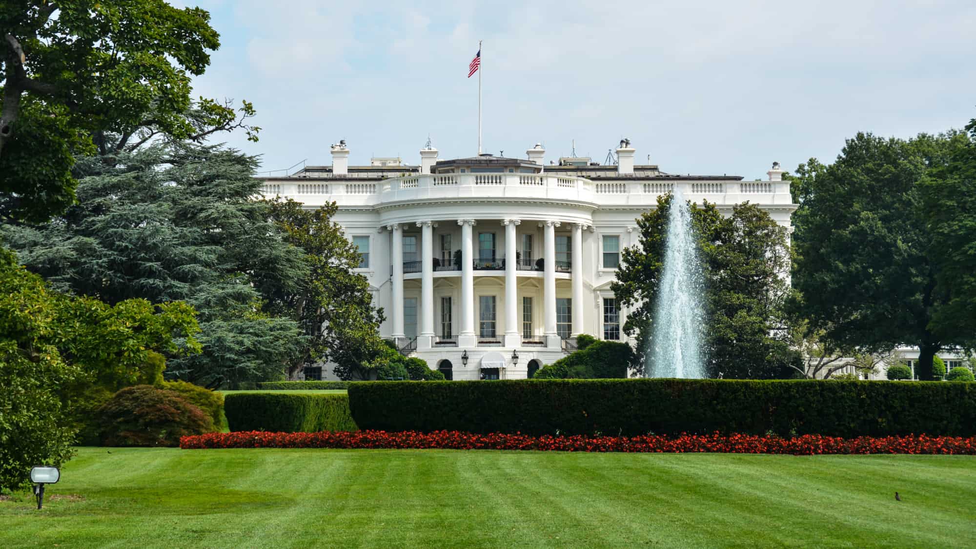 White House south view with fountain and flag, symbolizing U.S. policy impact on compliance strategies.