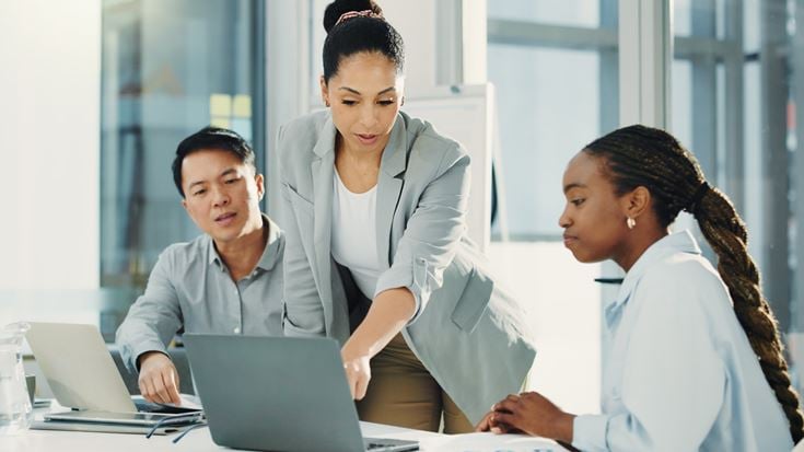 Team collaborates around laptops, representing financial crime compliance health checks and maturity assessment discussions.