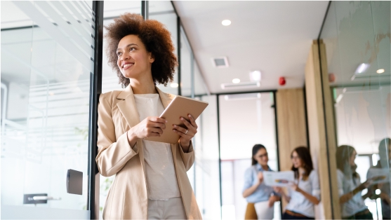 A woman in a business suit uses a tablet to highlight strategies for reducing stress in financial crime regulatory exams.