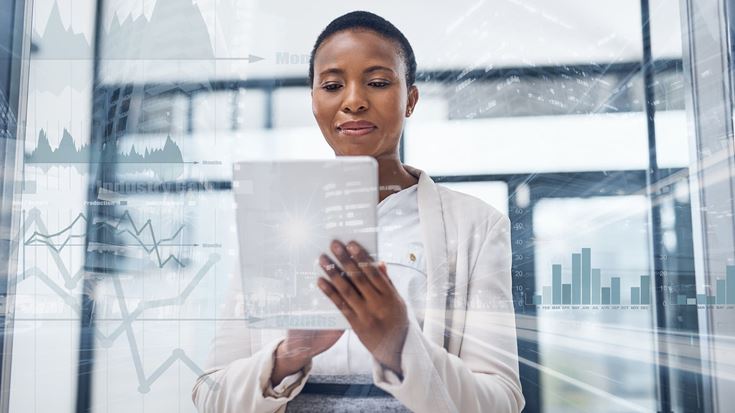 A woman in an office looking up ERP software on a tablet.