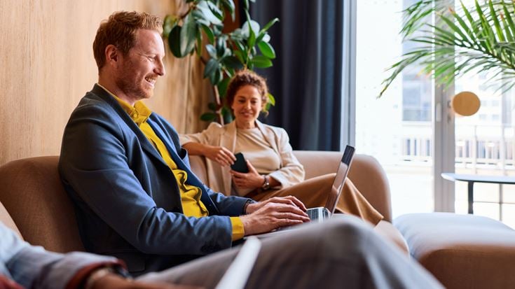 Two professionals collaborate in a lounge while reviewing FASB’s proposed hedge accounting amendments to ASC 815 on a laptop.