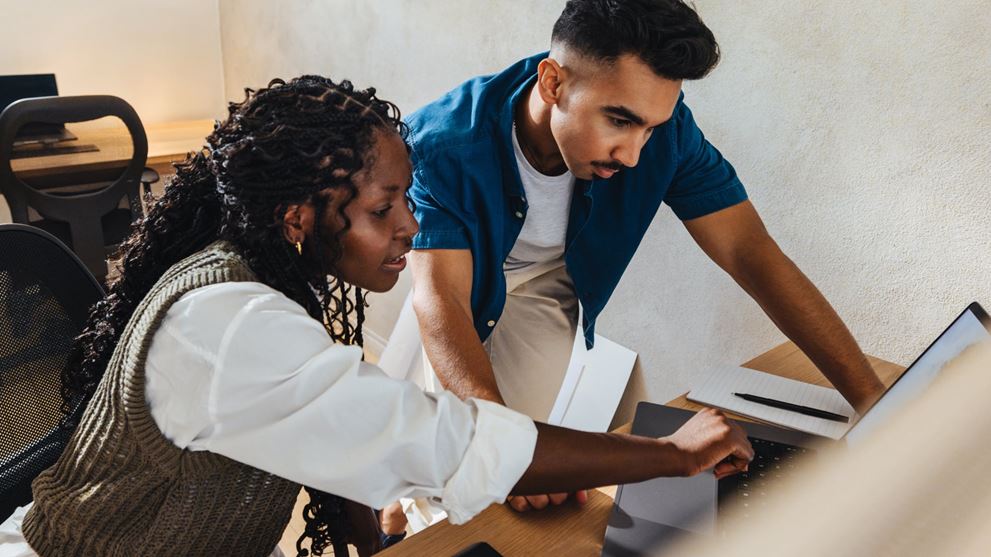 Two professionals review information on a laptop related to financial reporting and accounting considerations.
