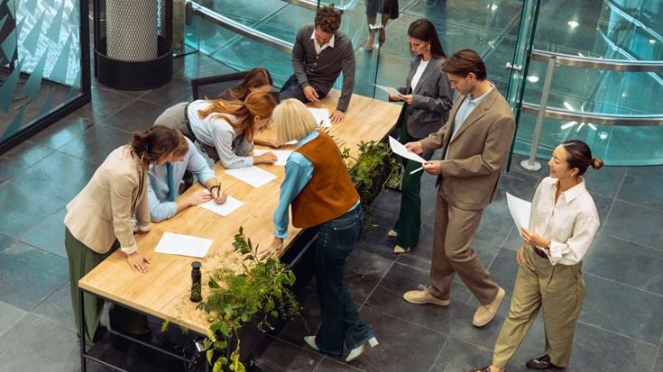 Business professionals review documents and collaborate around a table, representing shareholder governance and proxy processes.