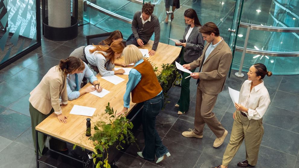 Business professionals review documents and collaborate around a table, representing shareholder governance and proxy processes.