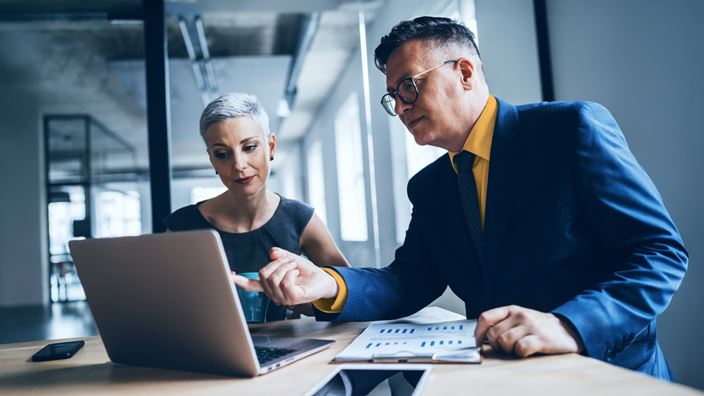 Two professionals reviewing data on a laptop, representing planning for SEC reporting rule changes.