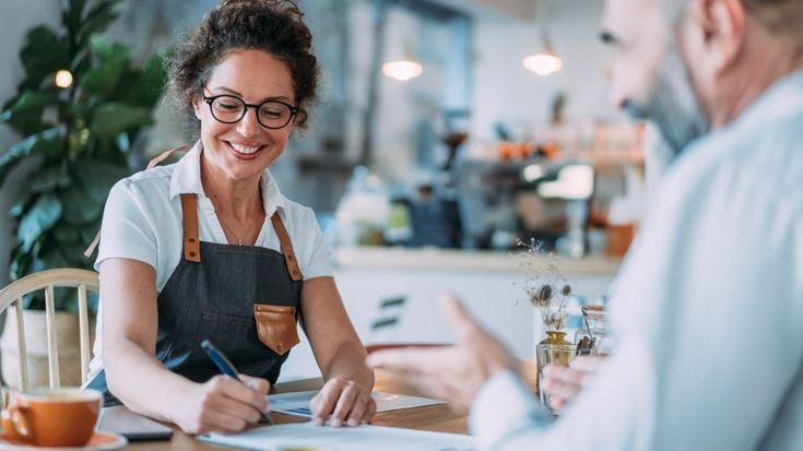 Small business owner reviews ERC filing documents with an advisor at a café table.