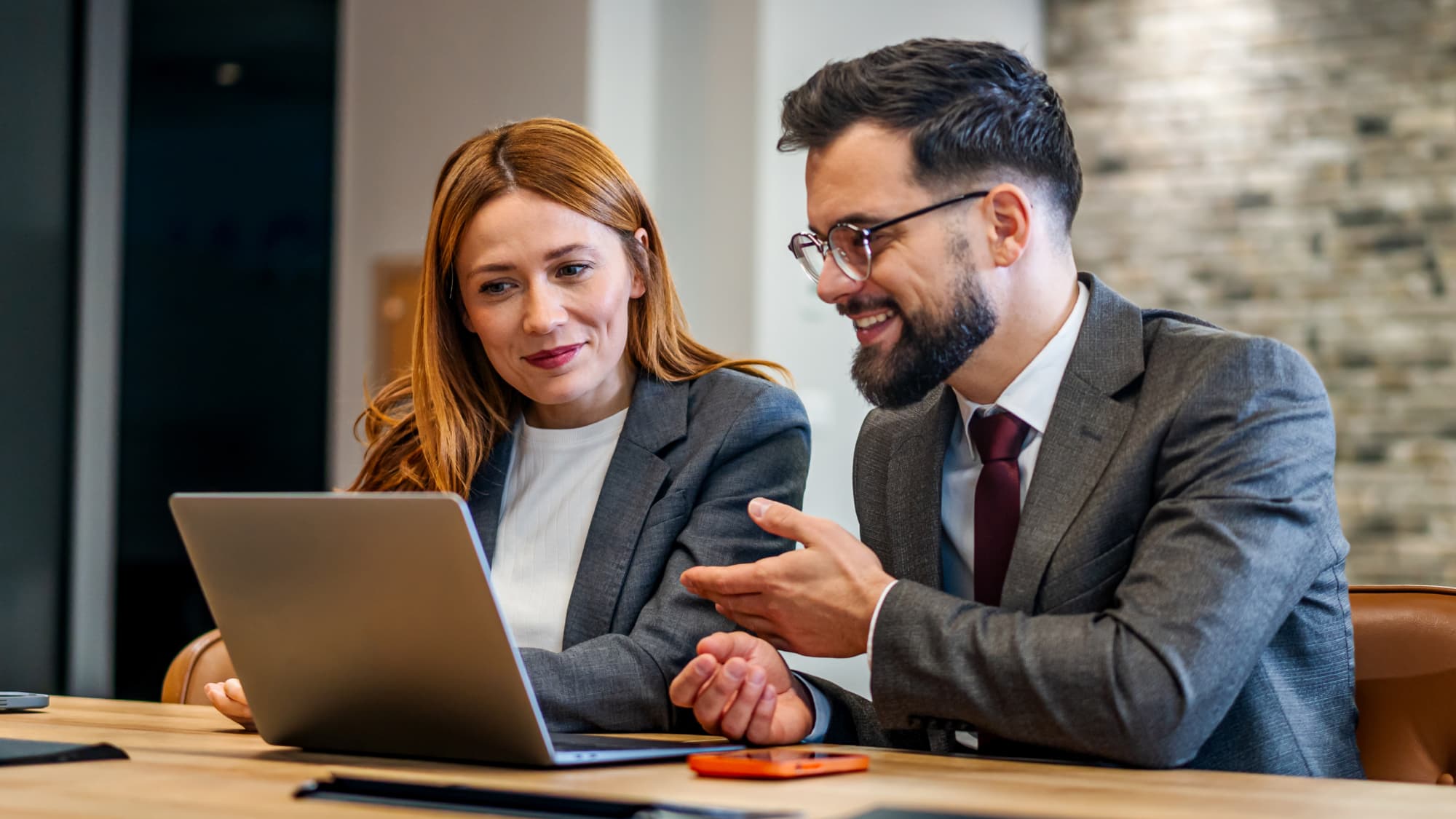 Two professionals discussing APAs at a laptop computer.
