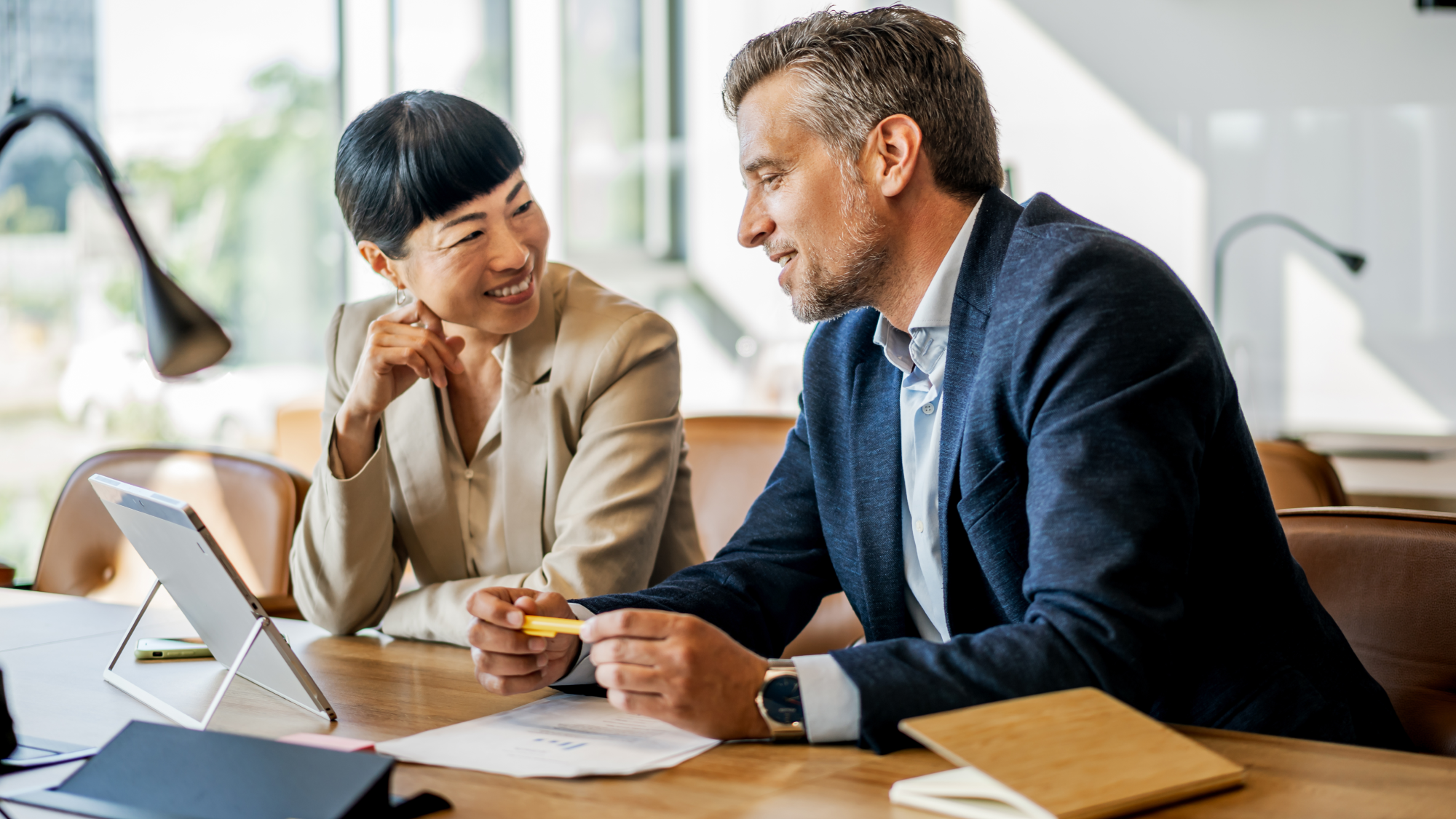 Two professionals review tax documents together as they discuss IRS penalty relief program changes.