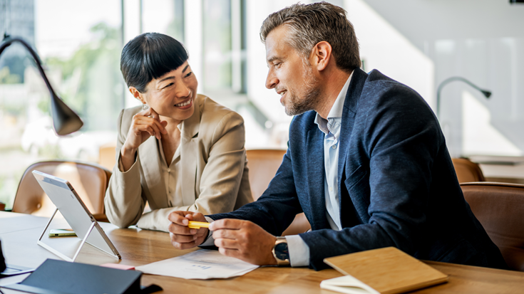 Two professionals review tax documents together as they discuss IRS penalty relief program changes.