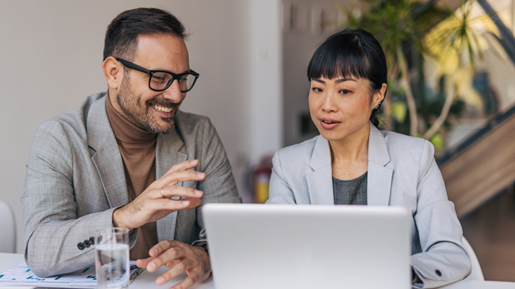 Two business professionals review information on a laptop while discussing federal tax election relief options.