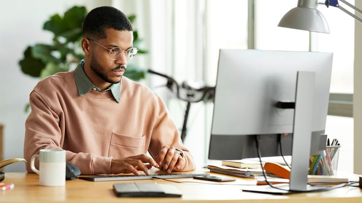 Professional works at a computer in a bright office, representing preparation for upcoming San Francisco and Los Angeles tax filing deadlines.
