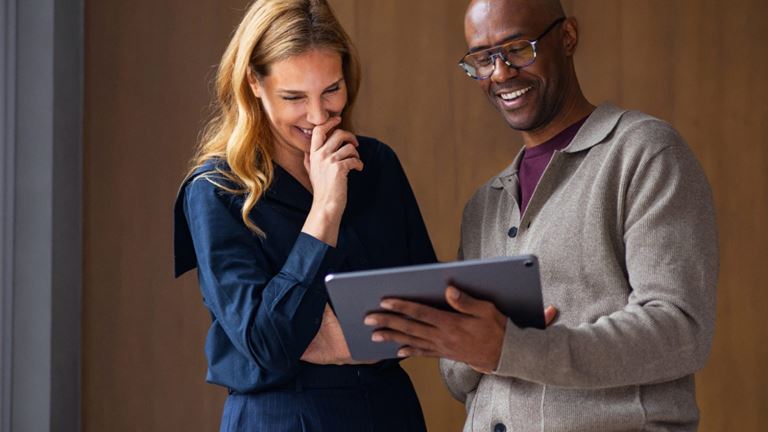 Two professionals reviewing a tablet