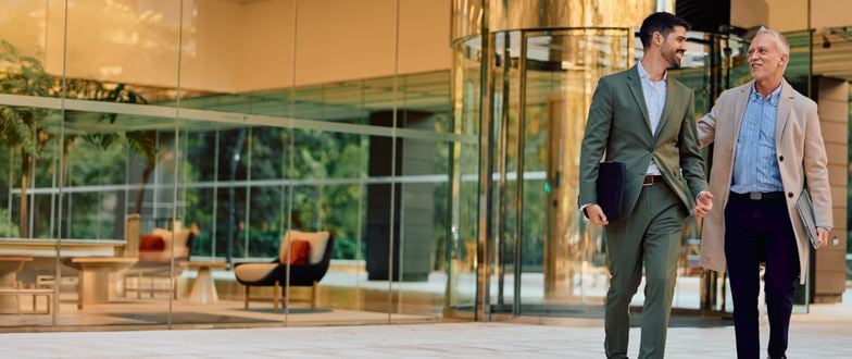 Two audit professionals walking together outside an office building, discussing audit and assurance services