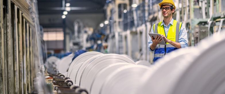 Technician reviews production data on a tablet in a plastics facility, representing efficiency and traceability in manufacturing operations.