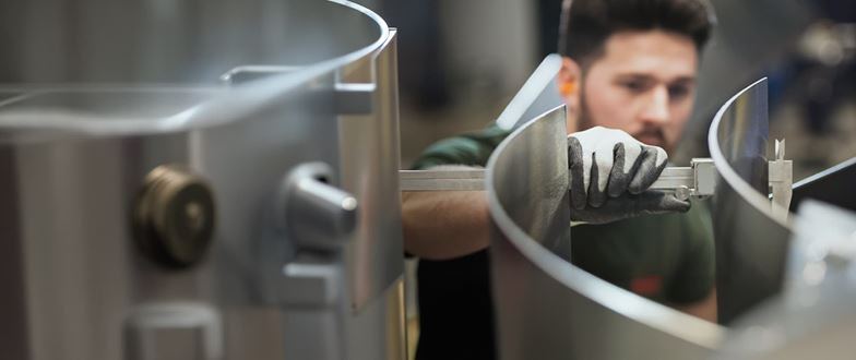 Metals worker measures a fabricated component during production.