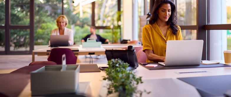 Professional uses a laptop in a shared workspace, supporting connected customer relationship management.