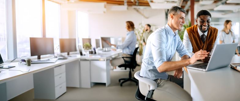 Two colleagues collaborate on a laptop in a modern office.
