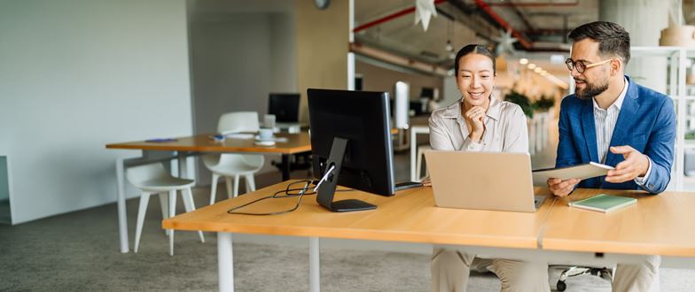 Two colleagues work together at a computer in a modern office.