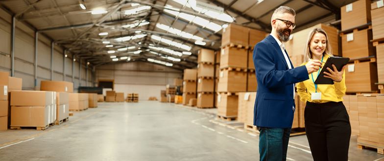 Professionals reviewing logistics data in a warehouse, illustrating technology-enabled customs and trade operations.