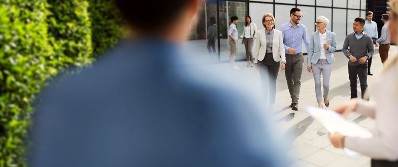 Business professionals walk and collaborate outdoors, representing state and local tax compliance strategy support.