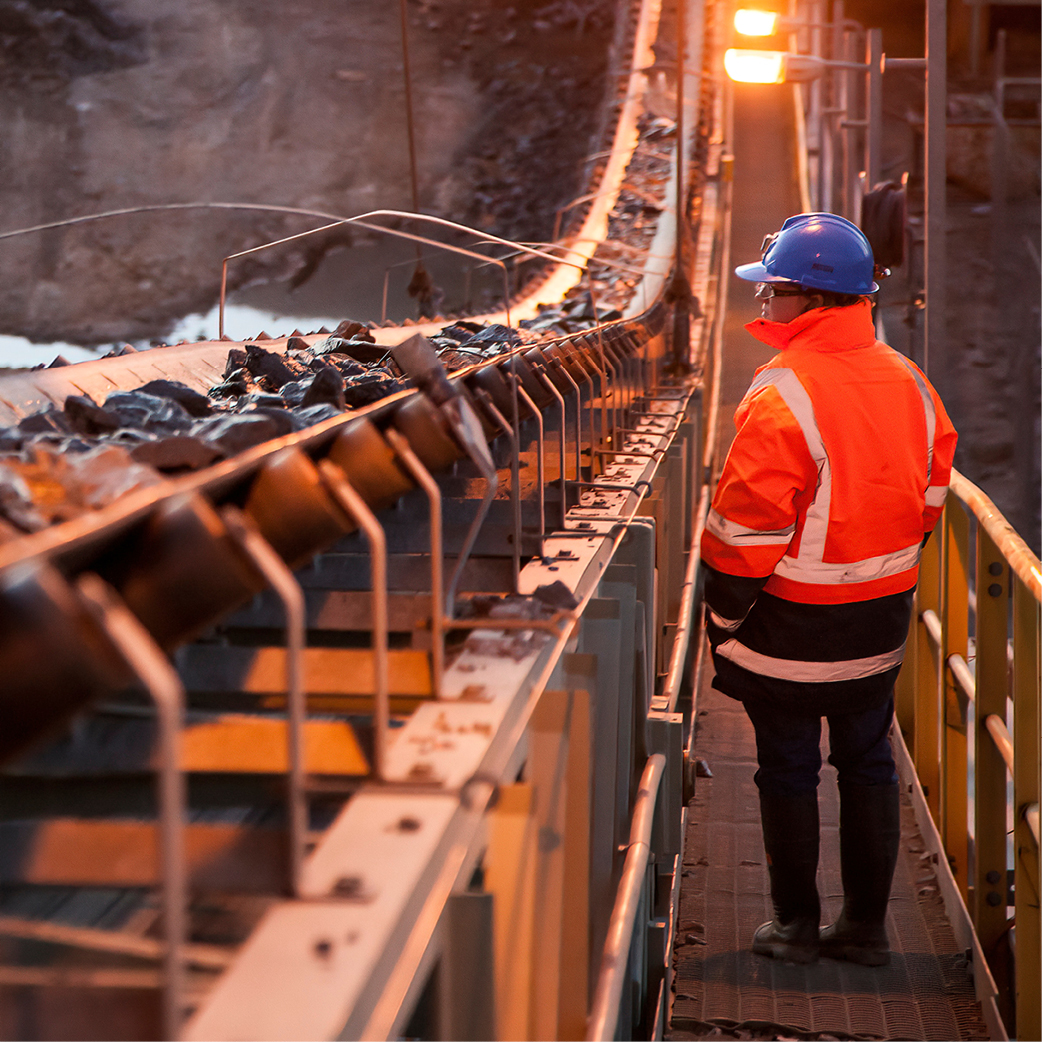 Mine worker watching conveyer belt with coal