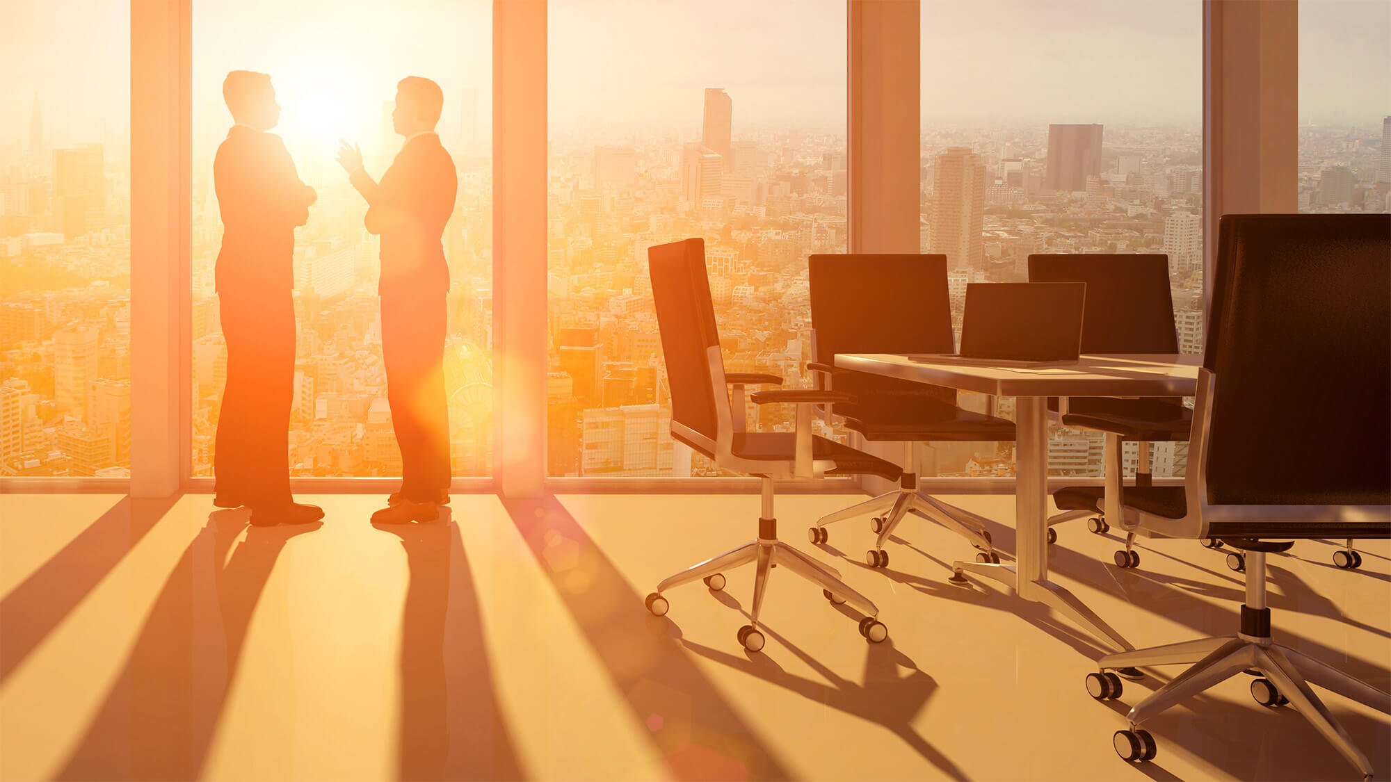 two corporate staff standing by the window in an office, having a conversation