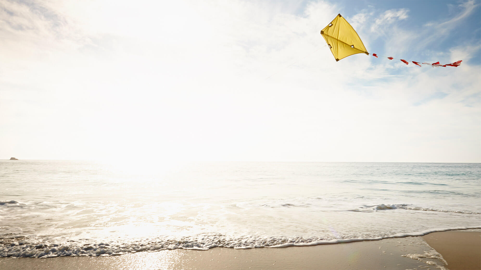 Yellow kite flying over a beach
