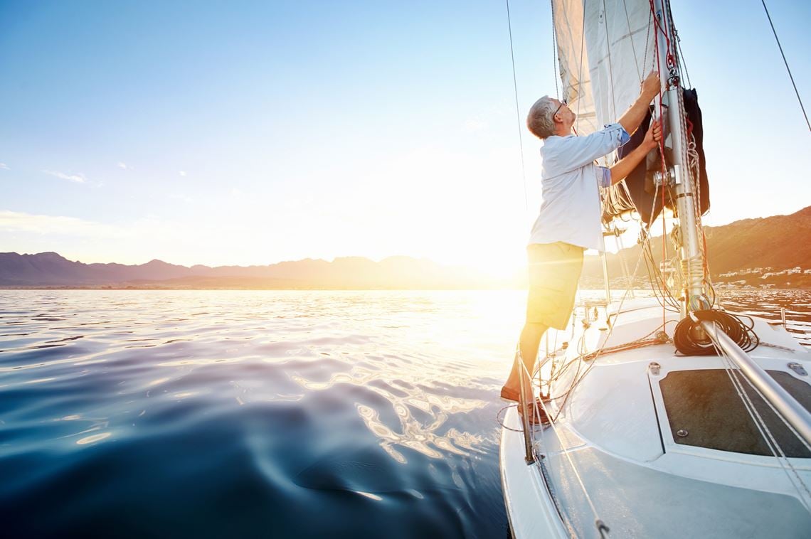 Hombre navegando en un velero asegura los nudos de la vela mayor