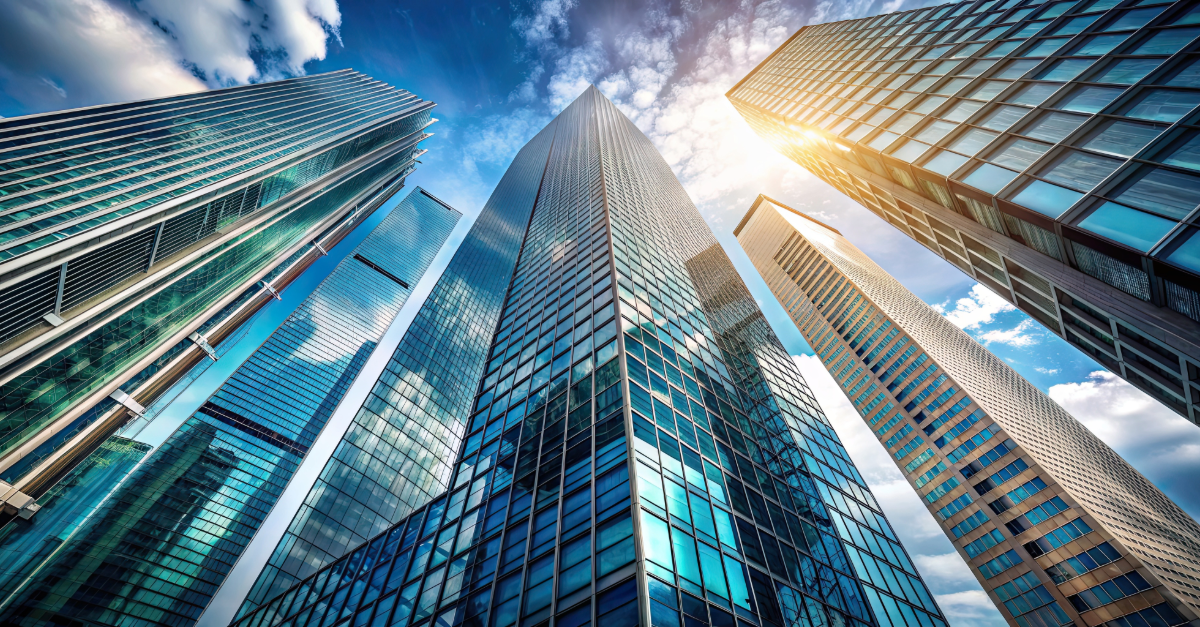 A street-level view of several skyscrapers, looking straight up