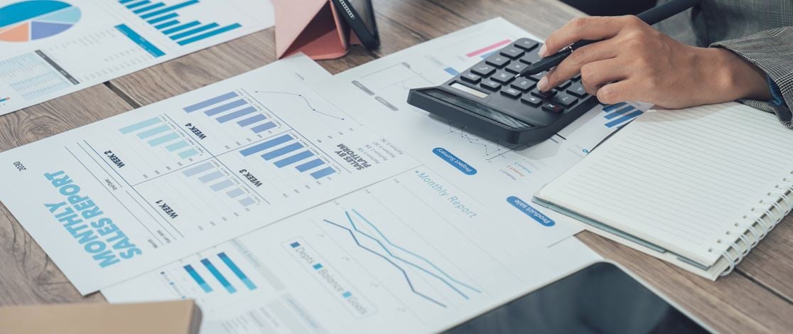 A person working on sheets of figures with a calculator