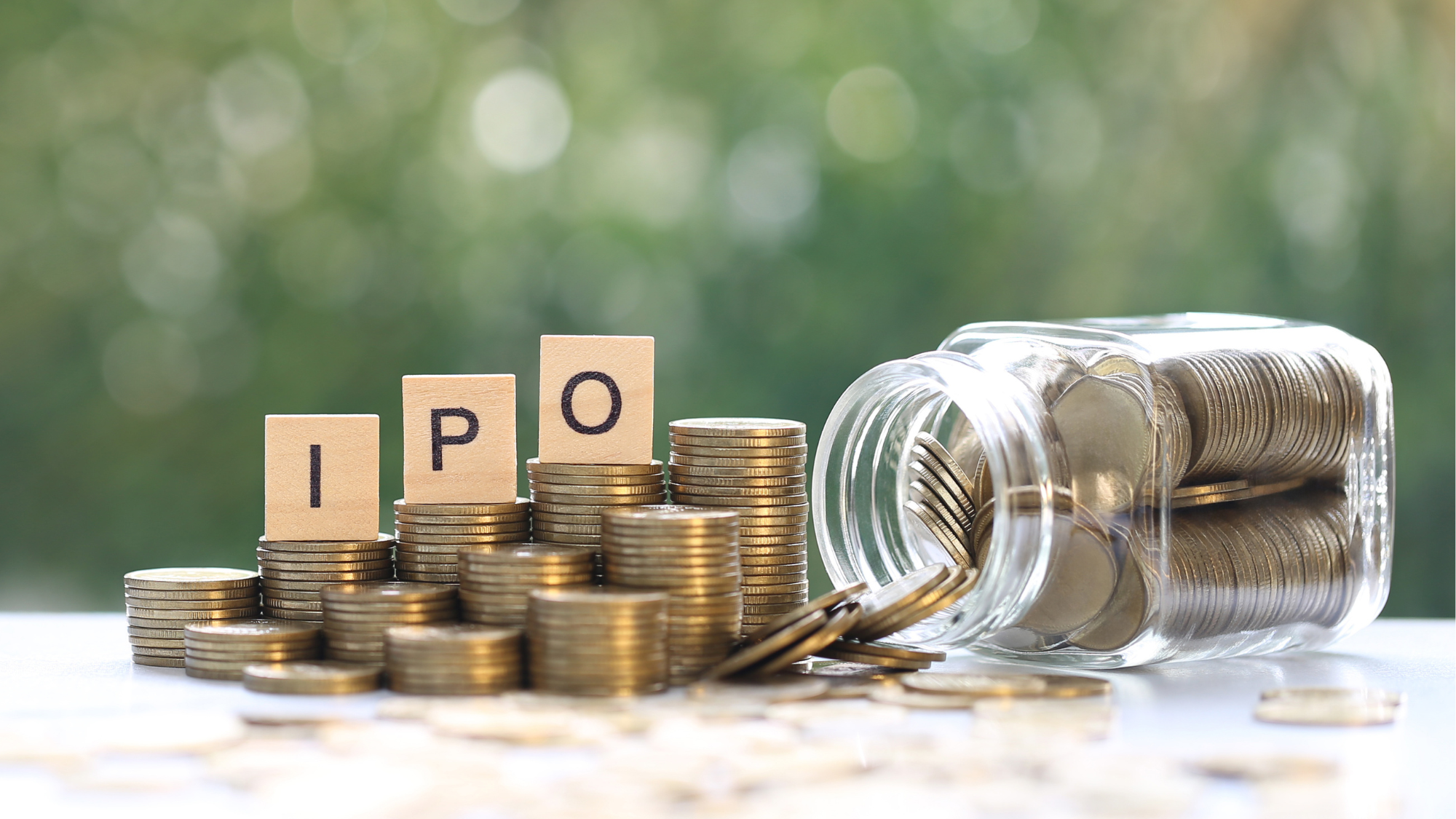 IPO written on stacked coins next to an overturned glass jar