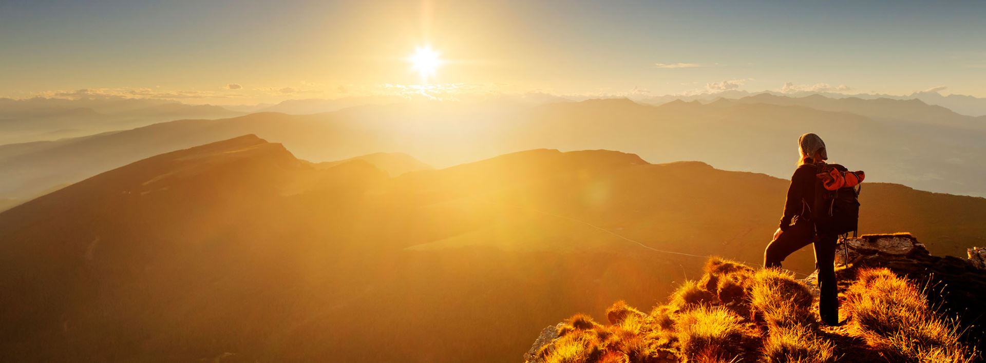 Person på fjelltopp i soloppgang/solnedgang.