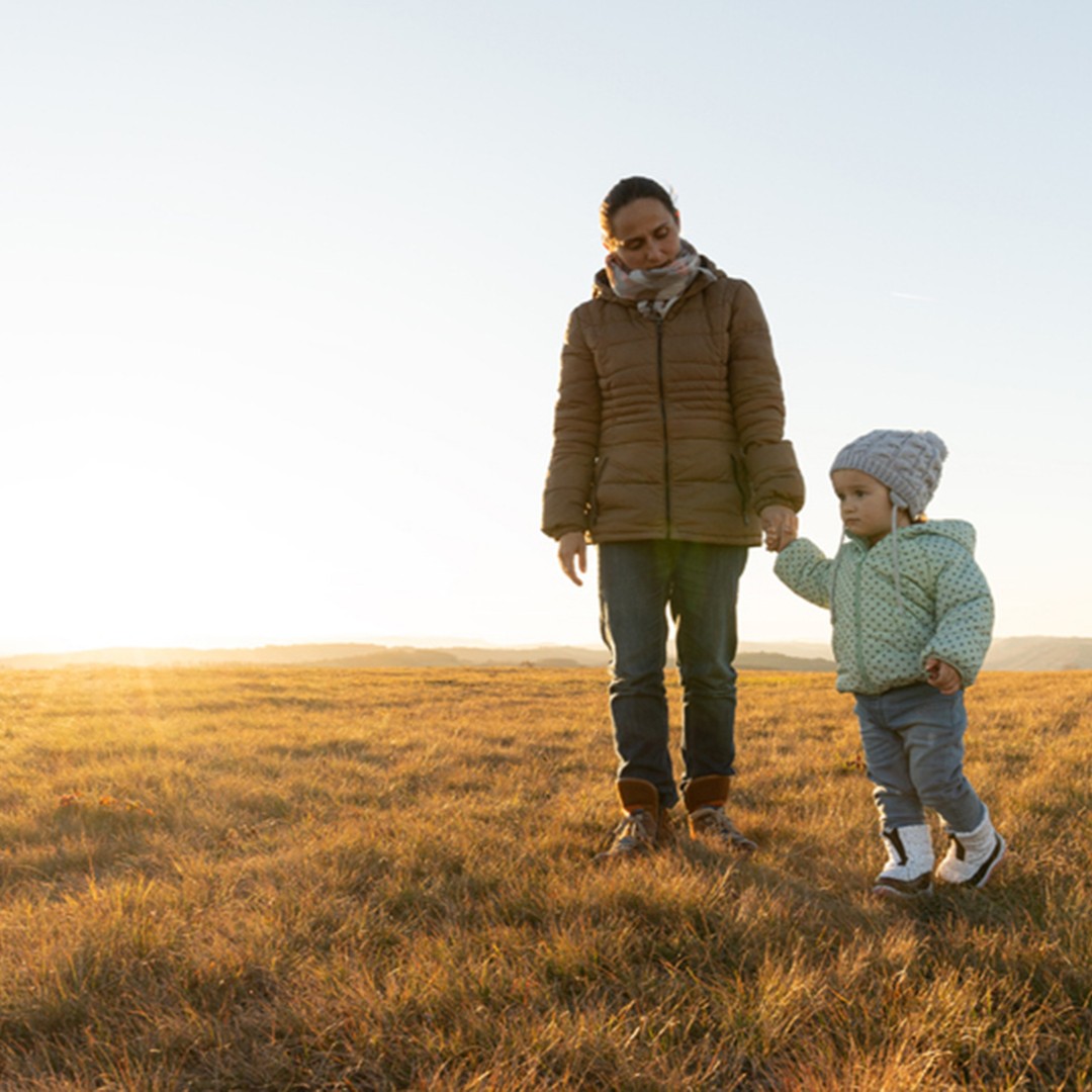Mother and son holding hands and walking in a field
