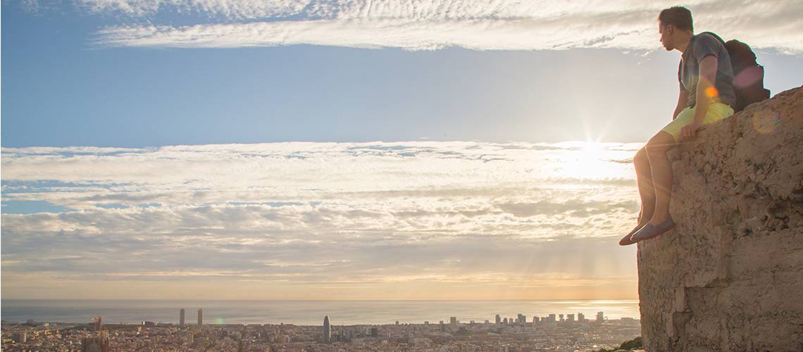 Man on a cliff overlooking a city
