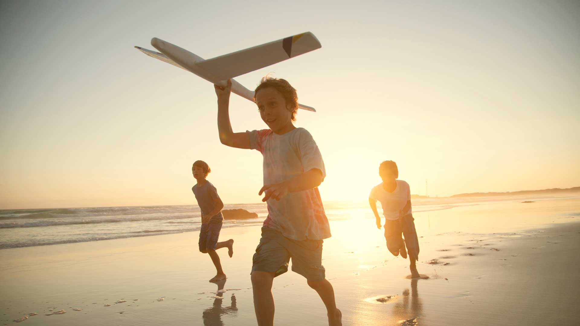 Boys on beach with toy plane