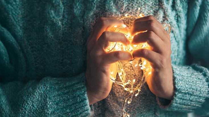 holding lights to chest in heart shape