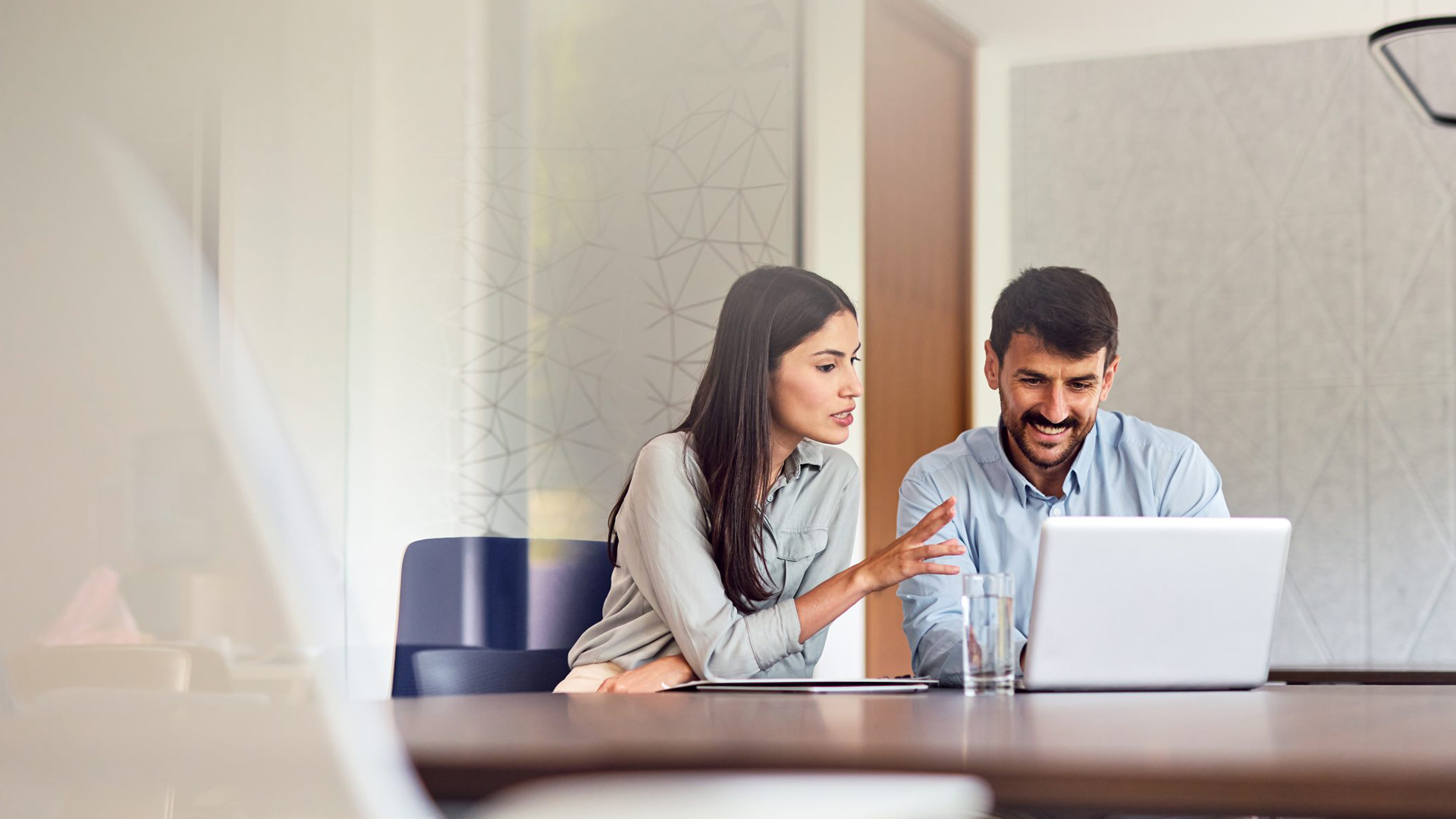 Man and woman talking in meeting room with laptop