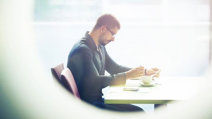 Man-sitting-at-table-with-window-scene