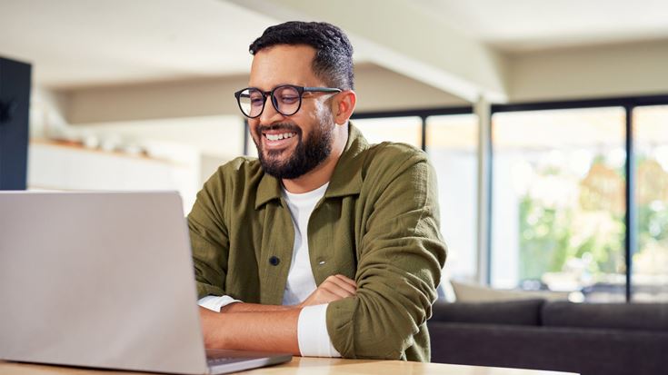 man smiling at laptop at home