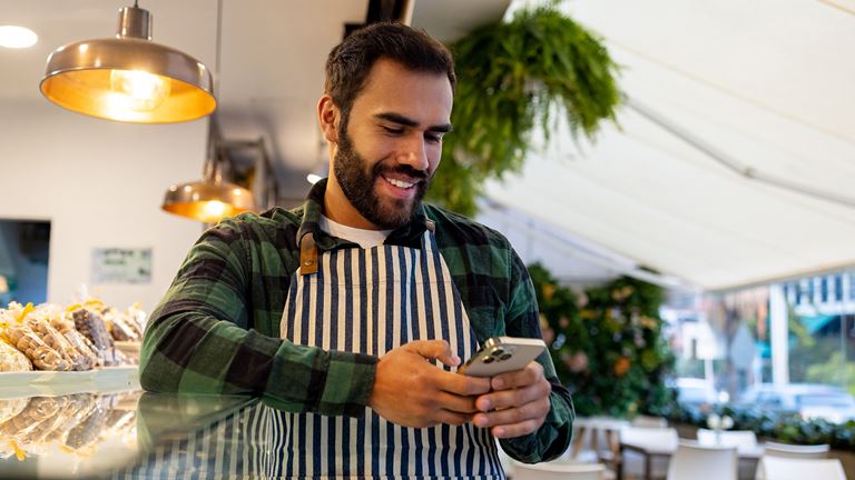 man with apron on his phone