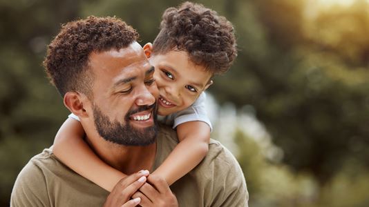 A man with child hugging his neck