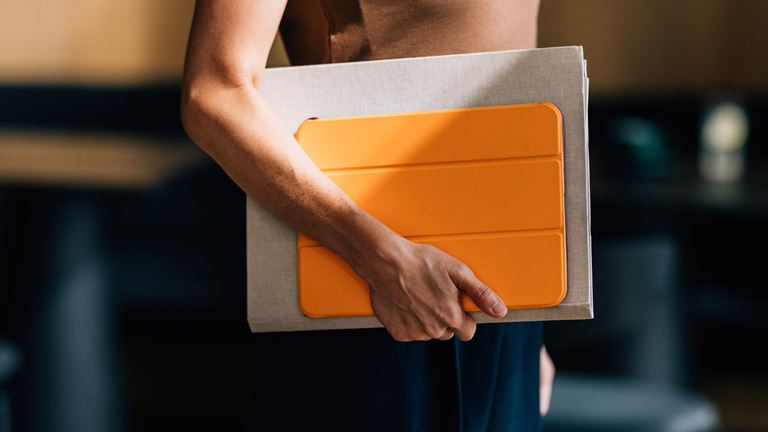 Person holding orange tablet and folder