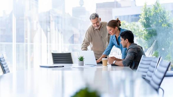 three people looking at laptop in meeting room