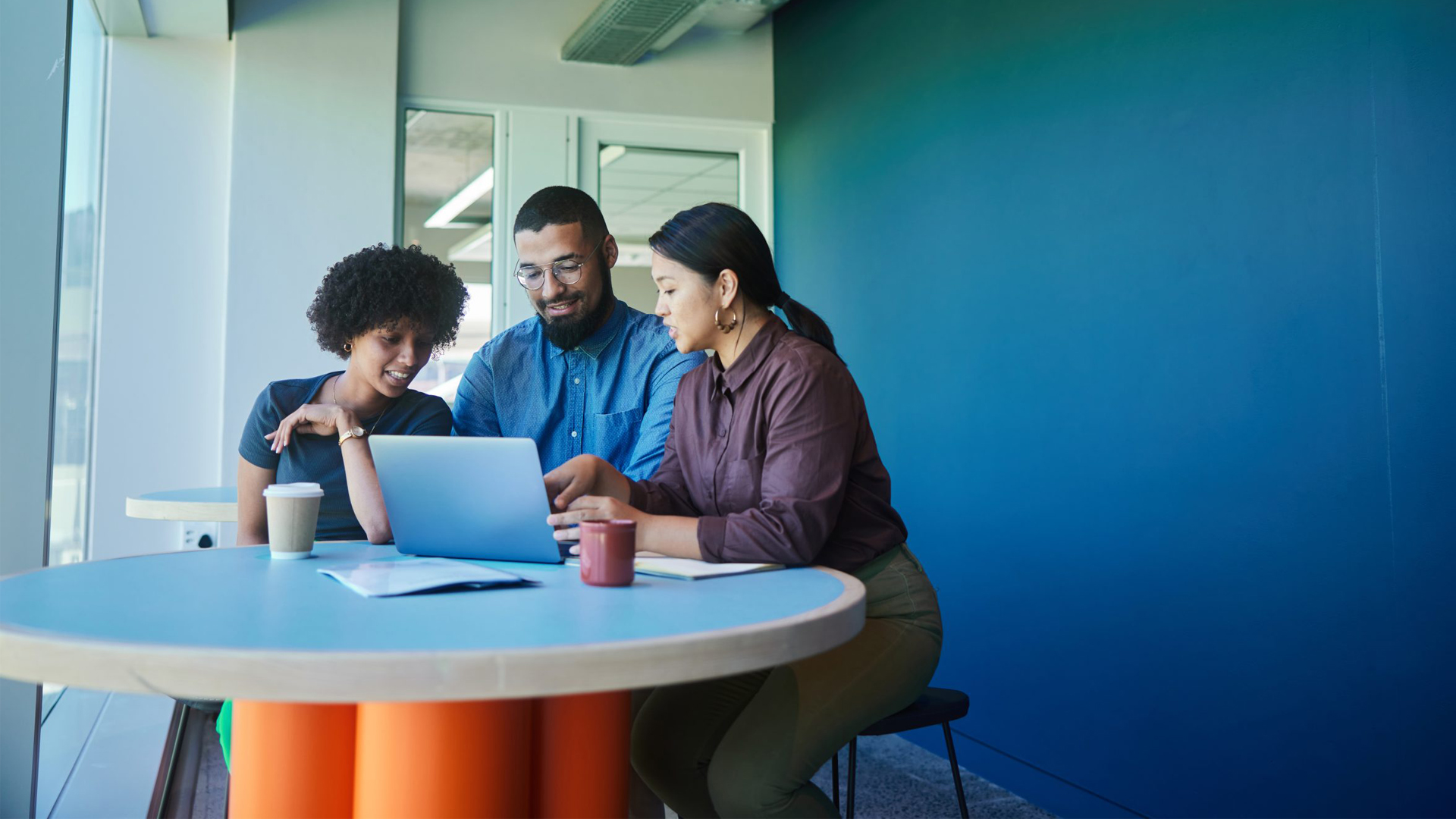 three people sitting at table with blue wall behind